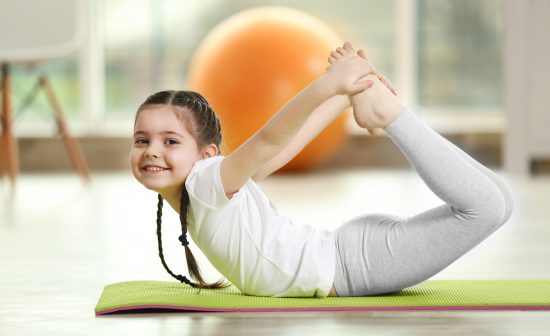 Little cute girl practicing yoga pose on a mat indoor