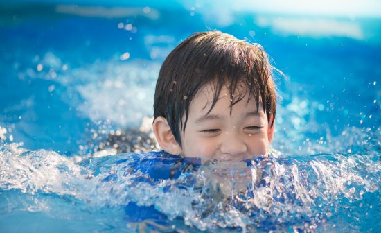 Cute Asian boy swimming and playing in a pool