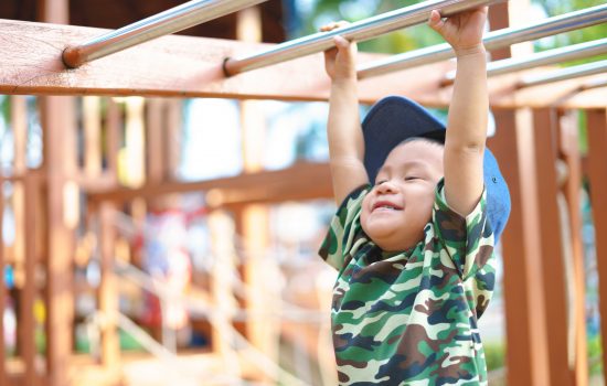 Asian boy about 1 year and 9 months in military suit playing at kid training playground for muscle development