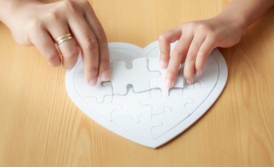 Hands of little girl playing jigsaw puzzle with her mother for family concept shallow depth of field select focus on hands