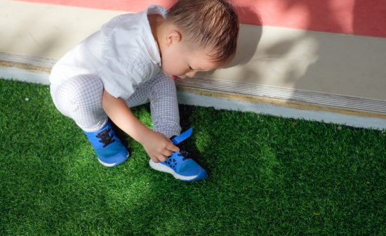 Cute little Asian 18 months / 1 year old toddler boy child sitting and concentrate on putting on his own blue shoes / sneakers, Encourage Self-Help Skills in Children, Develop Confidence concept