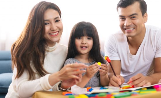 Portrait of happy family daughter girl is learning to use colorful play dough blocks toy together with parent