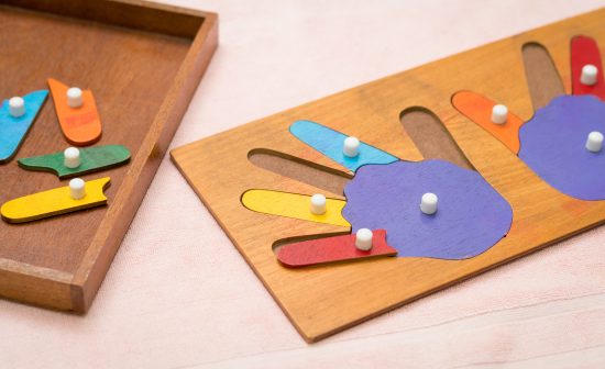 Top view closeup of colorful wooden Montessori sensorial material learning, hands and fingers. Preschool and Kindergarten educational toys, Logical sense, Cognitive skills, Learn Through Play tools.