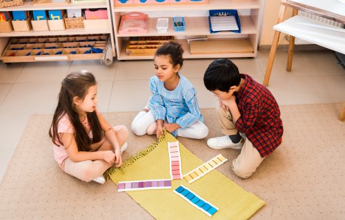 High angle view of children playing game while sitting on floor in montessori class