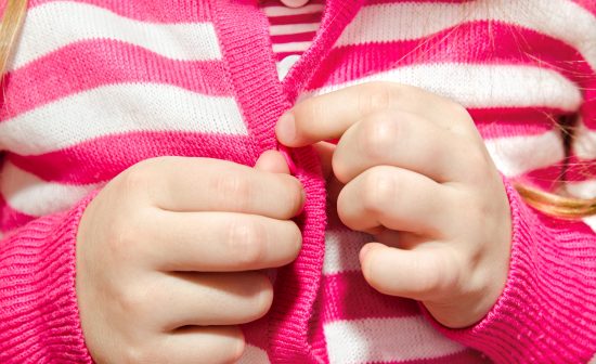 Little girl buttoning her jacket closeup