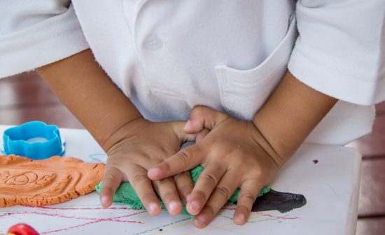 Child hand playing with clay, play doh