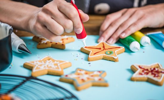 woman decorating gingerbread Christmas cookies with icing sugar