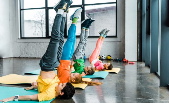 Preteen children doing candlestick exercise in gym