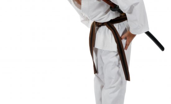 Teenage caucasian boy wearing a karate uniform with a katana bowing