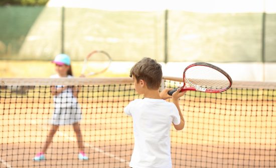 Cute little children playing tennis on court