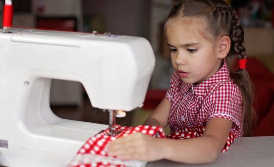 Young preschool girl working on sewing machine, creative tailor workshop, holiday handmade decoration