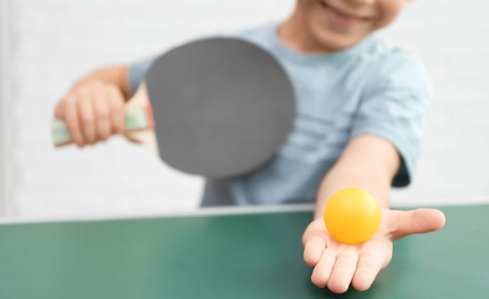 Cute little boy playing table tennis indoors